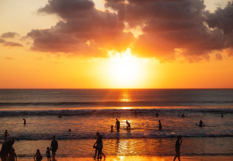 Beautiful sunset over the sea and silhouette of different people on the beach